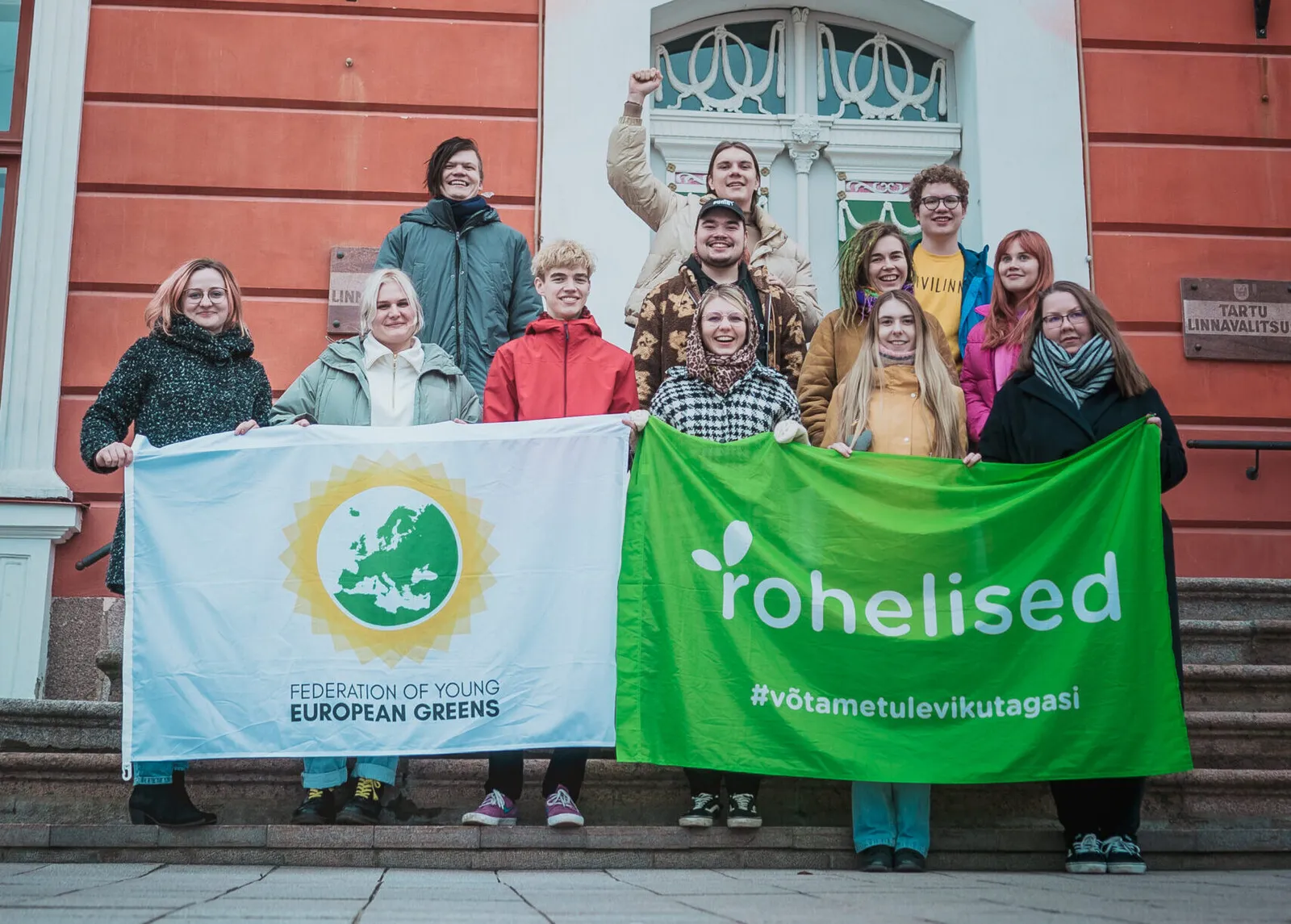 Noored Rohelised Tartu Raekoja ees Federation of Young European Greens ja Eestimaa Roheliste lippusid hoidmas.